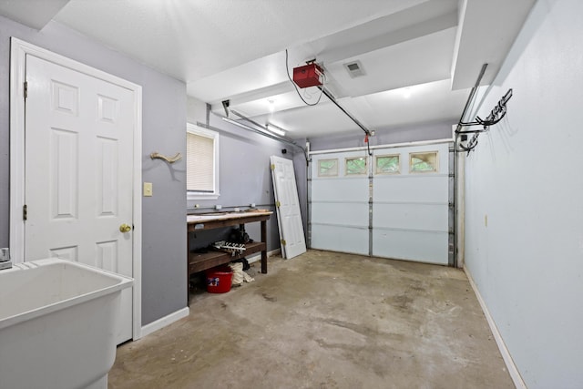 garage featuring baseboards, visible vents, a garage door opener, and a workshop area