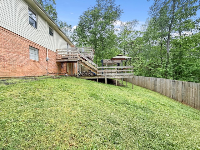 view of yard with a deck, a gazebo, stairway, and fence