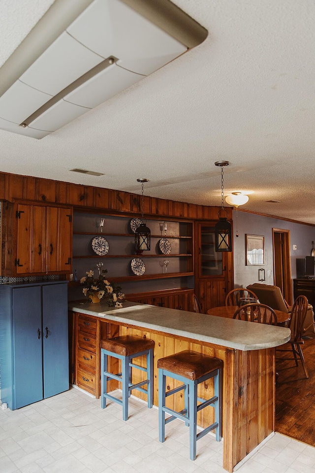 kitchen featuring light floors, open shelves, a breakfast bar area, and a textured ceiling