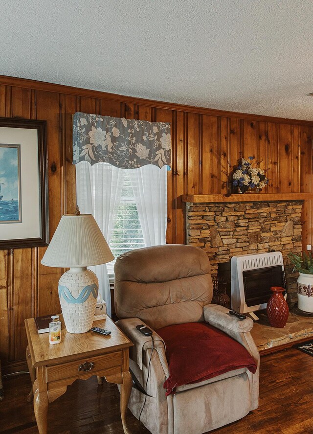 living area featuring wooden walls, a textured ceiling, heating unit, wood finished floors, and ornamental molding