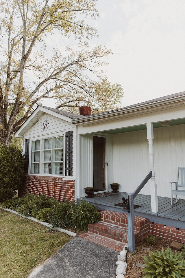 entrance to property with a chimney and brick siding