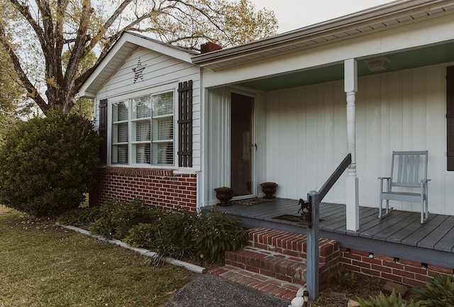 entrance to property with a porch and brick siding