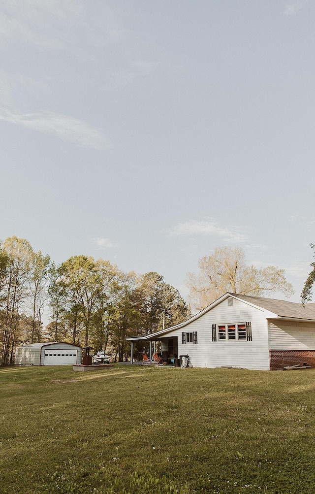 view of side of property featuring a lawn, brick siding, and a detached garage