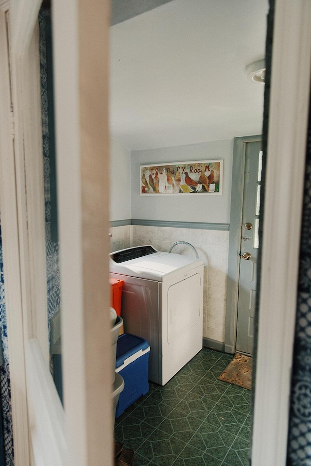 clothes washing area with laundry area, tile walls, and dark floors
