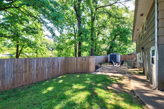view of yard with a storage shed, central AC, an outdoor structure, and a fenced backyard