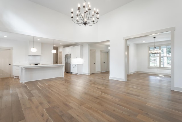 460 Spring Dr, Signal Mountain, TN 37377 - unfurnished living room featuring a towering ceiling, light wood finished floors, baseboards, and a notable chandelier