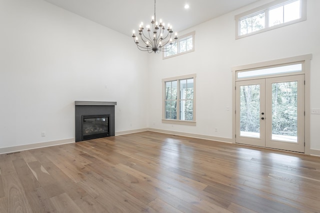 460 Spring Dr, Signal Mountain, TN 37377 - unfurnished living room featuring a towering ceiling, french doors, light wood-style floors, a chandelier, and a glass covered fireplace