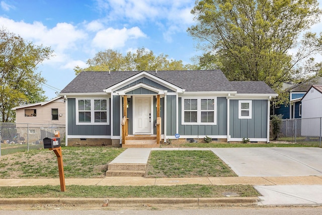 bungalow-style home featuring fence, a shingled roof, board and batten siding, crawl space, and a front yard