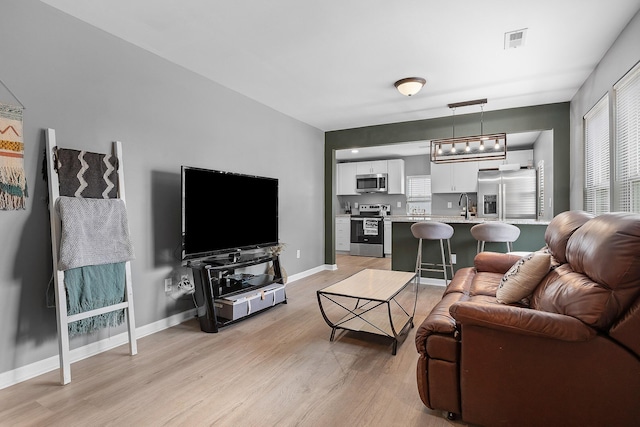 living area with light wood-type flooring, baseboards, and visible vents