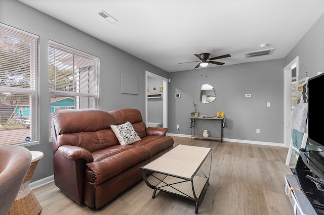 living room featuring baseboards, a ceiling fan, visible vents, and light wood-style floors