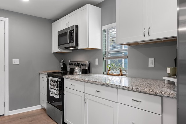 kitchen featuring white cabinets, light stone counters, stainless steel appliances, baseboards, and light wood-style flooring