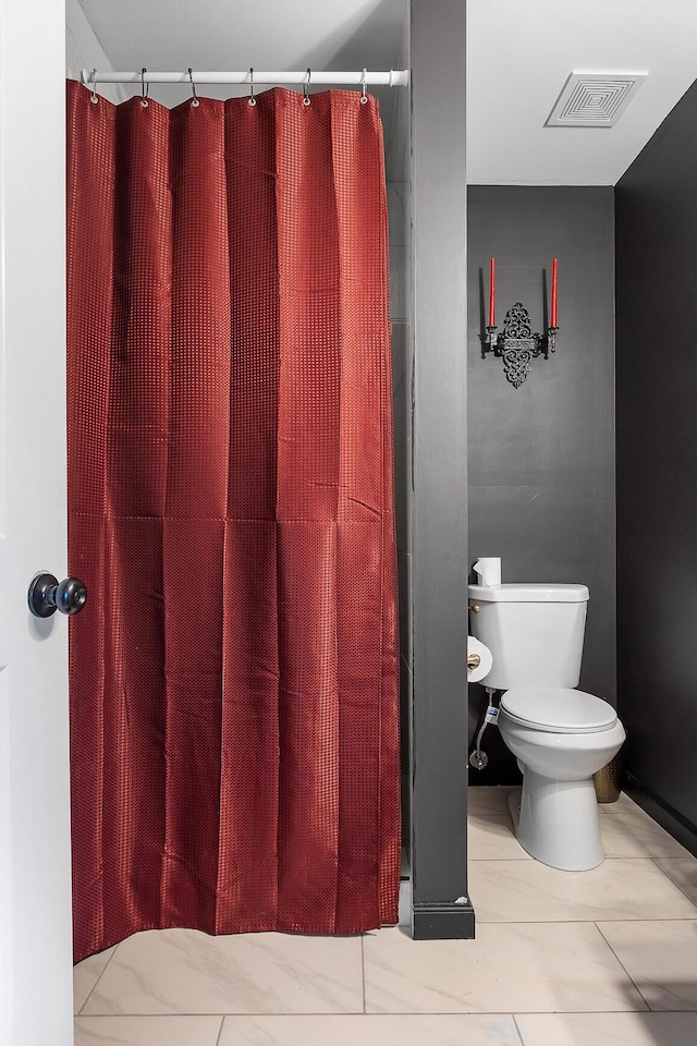 bathroom featuring a shower with shower curtain, visible vents, and toilet