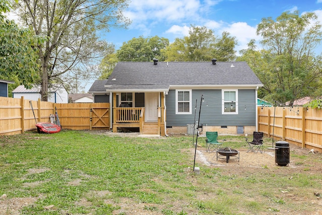 rear view of property with a fire pit, a yard, crawl space, and a fenced backyard