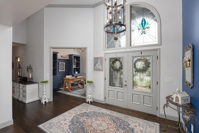 foyer featuring a towering ceiling, an inviting chandelier, french doors, and wood finished floors