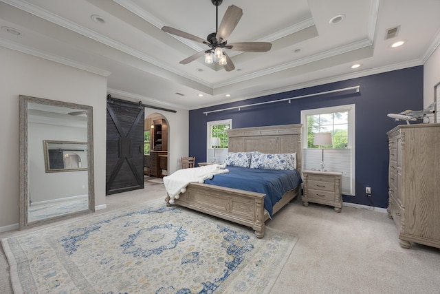 bedroom with a barn door, a raised ceiling, visible vents, light carpet, and ornamental molding