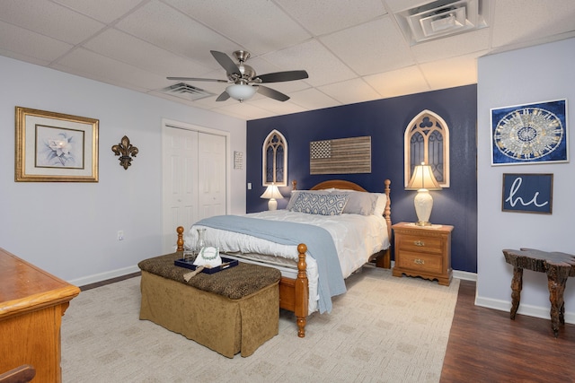 bedroom with baseboards, visible vents, wood finished floors, and a drop ceiling