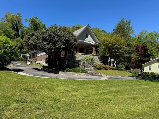 view of property hidden behind natural elements with brick siding and a front yard
