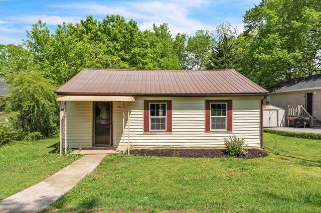 view of front of property with a storage unit, an outdoor structure, a front yard, and metal roof