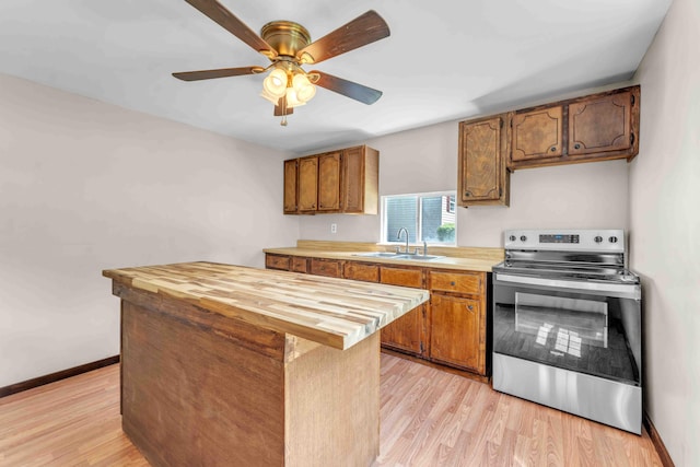 kitchen featuring a sink, light wood-style floors, electric stove, a kitchen island, and butcher block counters