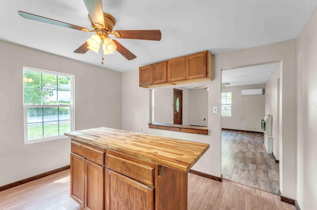 kitchen with baseboards, an AC wall unit, light wood finished floors, and butcher block countertops
