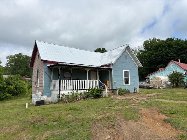 view of front of house featuring a porch, a front yard, and metal roof
