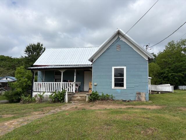 bungalow featuring covered porch, a front yard, and metal roof