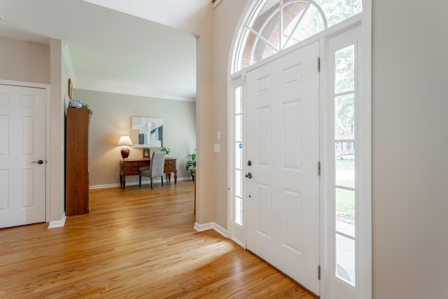 entryway featuring crown molding, plenty of natural light, and light wood-style flooring