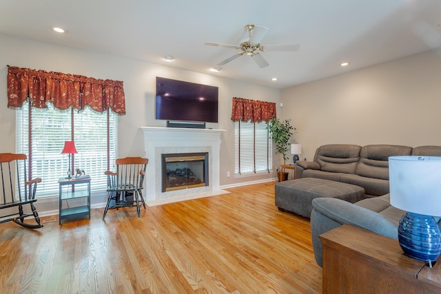 living area featuring a ceiling fan, a fireplace, wood finished floors, baseboards, and recessed lighting