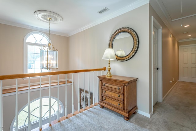 hallway with attic access, crown molding, baseboards, a notable chandelier, and carpet flooring