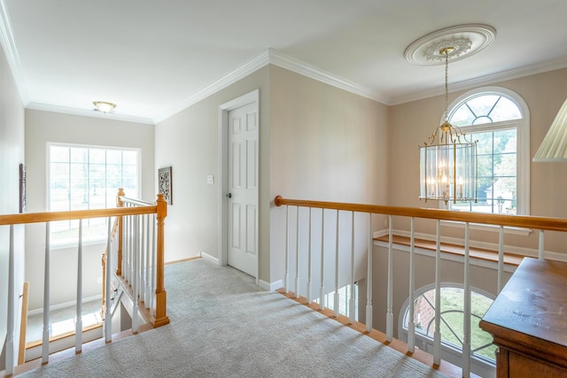 hall featuring crown molding, a notable chandelier, carpet floors, baseboards, and an upstairs landing