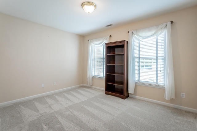 carpeted spare room featuring baseboards and visible vents