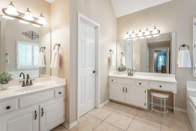 full bath featuring baseboards, two vanities, a sink, and tile patterned flooring