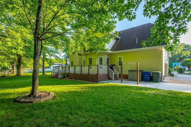 back of house featuring a yard, a patio, a wooden deck, and a shingled roof