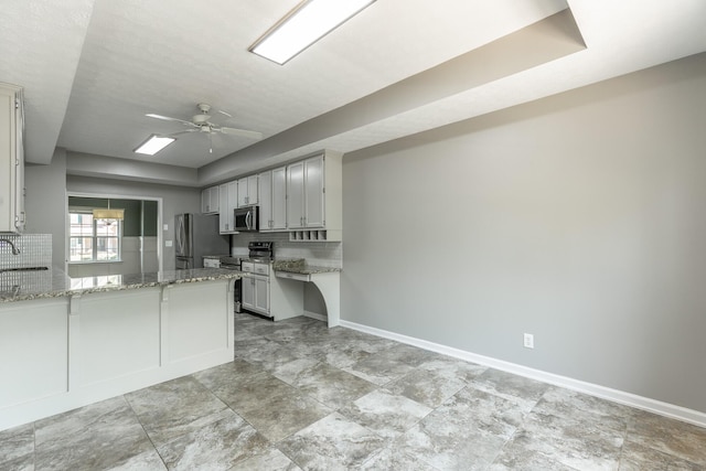 kitchen with light stone counters, tasteful backsplash, ceiling fan, stainless steel appliances, and a peninsula