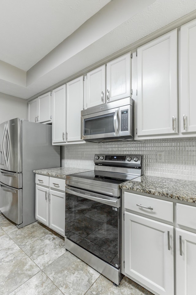 kitchen with appliances with stainless steel finishes, decorative backsplash, white cabinetry, and light stone countertops