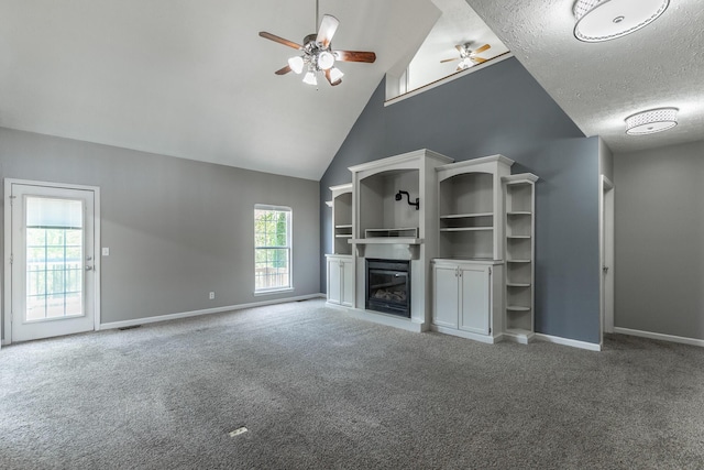 unfurnished living room featuring carpet, ceiling fan, a glass covered fireplace, baseboards, and a textured ceiling