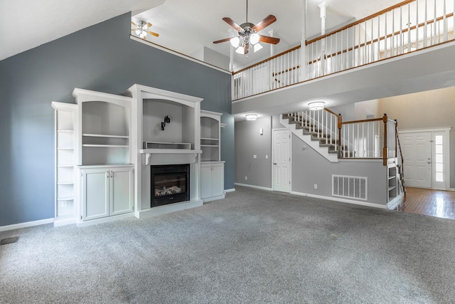 unfurnished living room with stairway, ceiling fan, high vaulted ceiling, visible vents, and baseboards