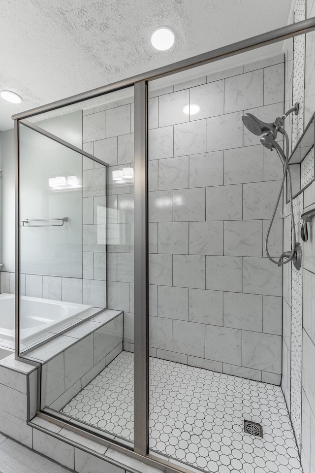 full bath with a stall shower, a textured ceiling, and a bath