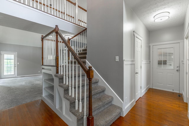 stairway with wood-type flooring, a textured ceiling, and baseboards