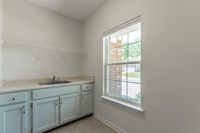 laundry room featuring baseboards, light tile patterned flooring, and a sink