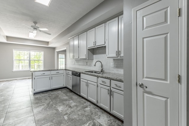 kitchen featuring stainless steel dishwasher, a sink, light stone countertops, a peninsula, and backsplash