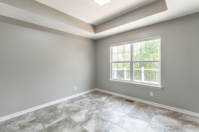 unfurnished room featuring a raised ceiling, visible vents, and baseboards