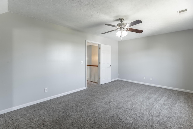 empty room featuring ceiling fan, visible vents, dark colored carpet, baseboards, and a textured ceiling