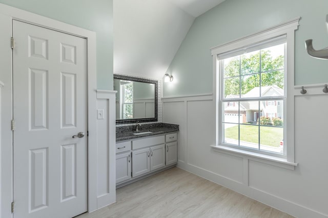 bathroom featuring a wealth of natural light, a wainscoted wall, vanity, and vaulted ceiling