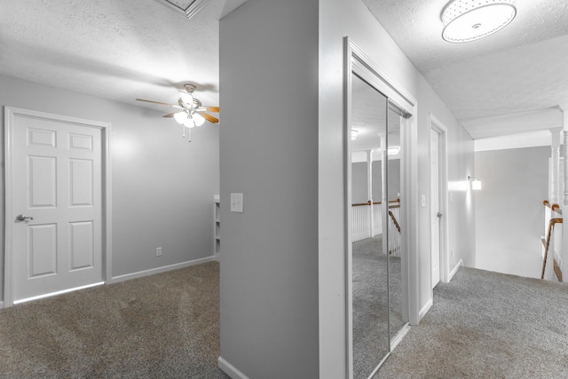 hallway featuring an upstairs landing, baseboards, carpet floors, and a textured ceiling