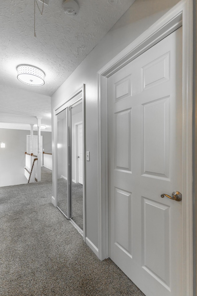 corridor with an upstairs landing, carpet, baseboards, and a textured ceiling