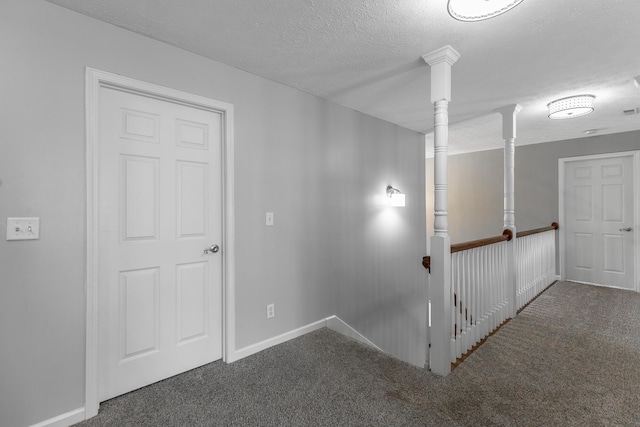 hallway featuring carpet, baseboards, and a textured ceiling