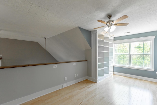bonus room featuring a ceiling fan, visible vents, baseboards, a textured ceiling, and wood finished floors
