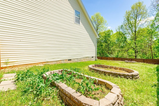 view of yard with a fire pit, fence, and a garden