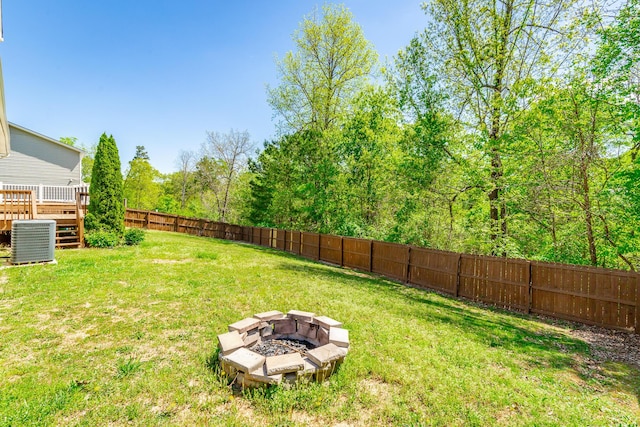 view of yard with a deck, a fire pit, a fenced backyard, and central air condition unit